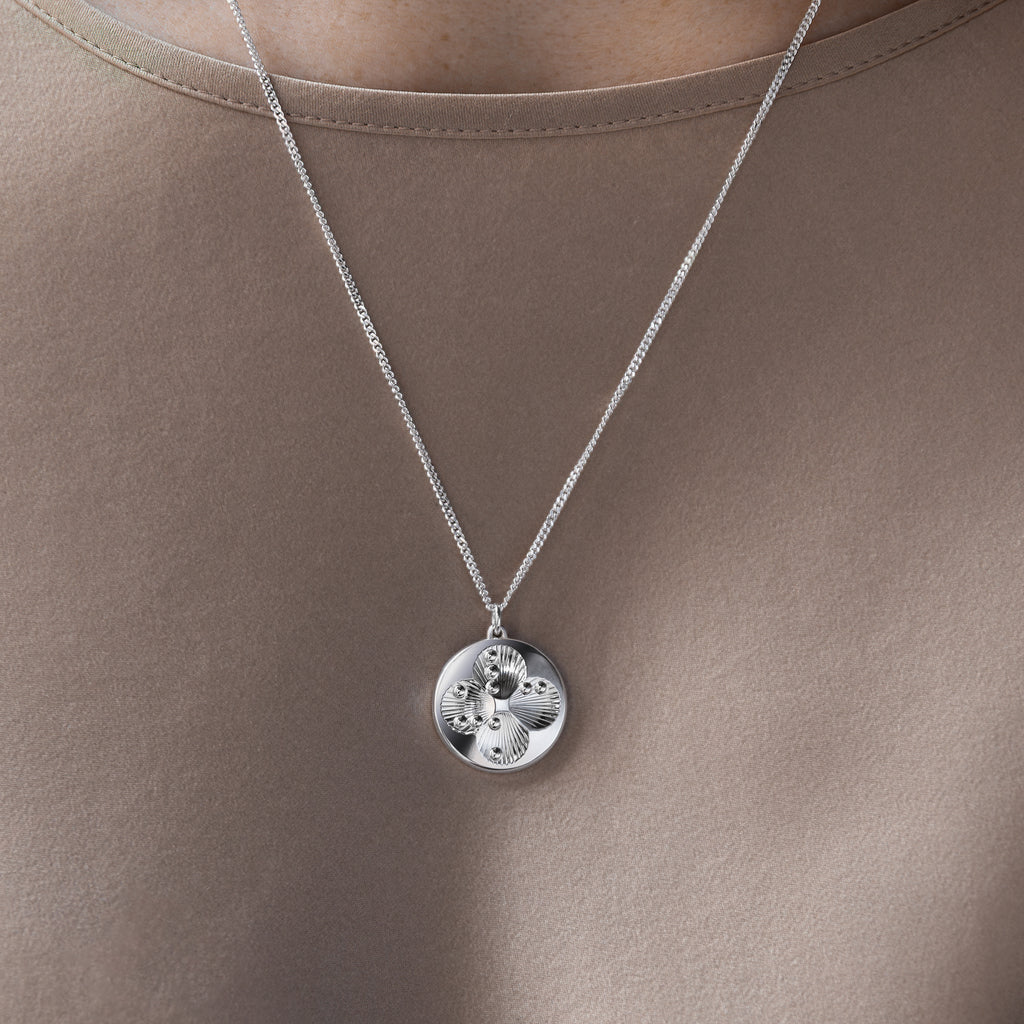 Lucky Dots silver pendant on a shimmering beige silk blouse, the silver reflecting the light beautifully.